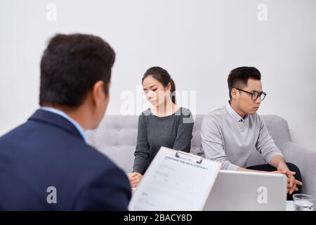 Junge wütend Paar betrogen, Investoren, auf die Papiere argumentieren mit männlichen real estate agent, niemandes Eigentum Käufer ihre Rechte schützen, zu Stockfoto