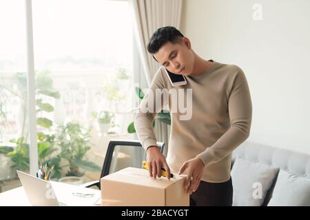 Mann öffnen zerbrechliches Paket aus dem Internet bestellt Stockfoto