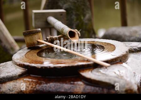 Wasserbecken des Temizuya Shinto Shrine in Kyoto, Japan. Pfanne ruht über dem Becken. Wasser tropft langsam. Stockfoto