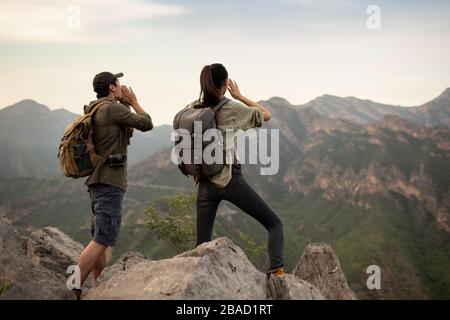 Junges chinesisches Paar, das auf dem Berggipfel schreit Stockfoto