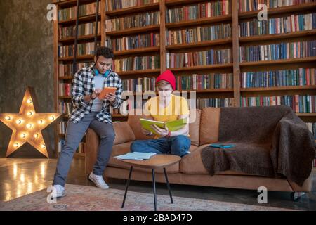 Junger Mann in einem gelben T-Shirt, der vor Prüfungen mit seinem Freund studiert Stockfoto