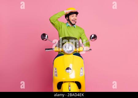 Porträt seines hübschen freundlichen fröhlichen fröhlichen fröhlichen Kerls mit Moped auf der Suche nach einer neuen Zielstraße isoliert über rosa Pastellfarbe Stockfoto
