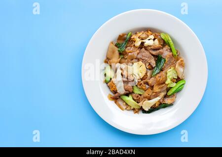 Gebratene flache Nudeln und Schweinefleisch mit Sojasoße rühren. Draufsicht, Kopierbereich Stockfoto