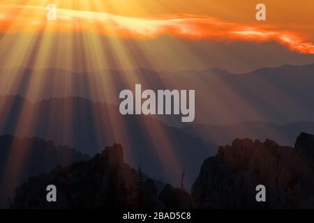 Sonnenuntergang auf dem Berg mit den Schichten der Hügel, beleuchtet von den Strahlen der aufgehenden Sonne Stockfoto