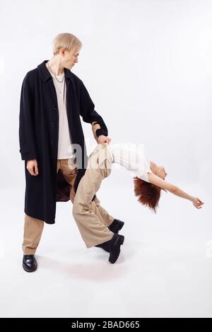 Ein großgewachsener Mann zieht ein Mädchen an seinen Gürtel. Das Mädchen wird zurückgeschlagen. Auf dem Mann befindet sich ein schwarzer Umhang und ein weißes T-Shirt. Stockfoto