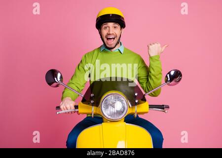 Porträt seiner schönen, attraktiven, überfreuten fröhlichen Kerl, der mit Moped reitet und cool Werbung für neue, über Rosa isolierte Lösung für die Entscheidung zeigt Stockfoto