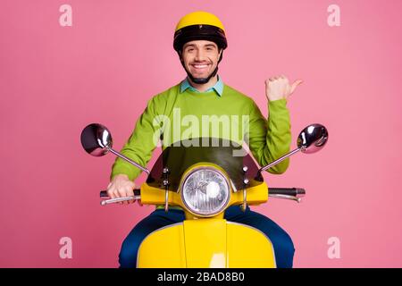 Portrait seines netten, selbstbewussten fröhlichen fröhlichen Kerls, der mit Moped reitet und Werbung für neue Neuheiten wie Follow Subscribe Solution isoliert zeigt Stockfoto