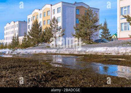 Quellbäche aus der Schneeschmelze im Frühjahr fließen zwischen Häusern, waschen schwache Böden weg und waschen das Fundament ab Stockfoto