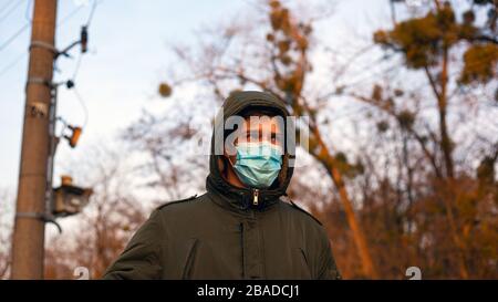 Junger Mann in medizinischer Schutzmaske steht auf der Straße. Quarantäne-Isolation-Pandemie 2019-nCoV. Coronavirus Grippe-Ausbruch. Stockfoto