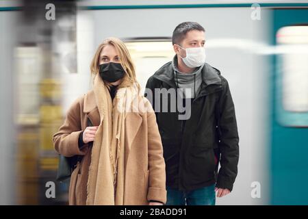 Brunet Mann und blonde Frau, die in medizinischen Masken in der Nähe des Autos in der U-Bahn zur Seite schauen. Coronavirus Epidemie. Stockfoto