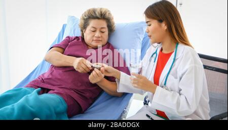 Der Arzt bittet und erklärt die Krankheit und gibt die Medikamente mit alten Frauen im Krankenhaus. Stockfoto