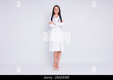 Großes Foto der schönen fröhlichen professionellen Dame gute Laune lächelnde Patientenarme gekreuzt tragen langes weißes Laborcoat Stethoskop High Heels Stockfoto