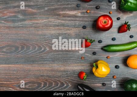 Obst, Gemüse, Nüsse, Beeren liegen auf einem wengenfarbenen Tisch Stockfoto