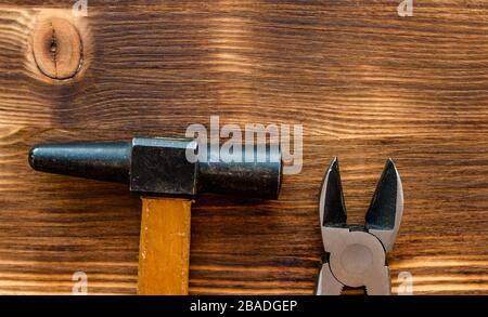 Alte Reparaturwerkzeuge Hammer, Zange, auf braunem Holzhintergrund. Konzept des Arbeitstages Stockfoto