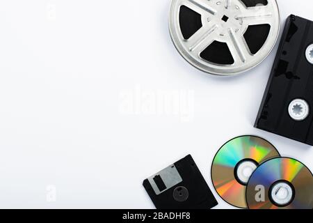 Draufsicht auf CD-Discs, schwarze VHS-Kassette, Diskette und Filmrolle auf weißem Hintergrund Stockfoto