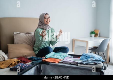 Muslimische Frauen danken Gott, nachdem sie ihre Kleidung vorbereitet haben, bevor sie in den Urlaub gehen Stockfoto