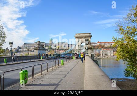 Budapest, Ungarn - 6. November 2019: Berühmte Szechenyi-Kettenbrücke, Hängebrücke, über die Donau in der ungarischen Hauptstadt. Touristen Sehenswürdigkeiten, Autos auf der Straße. Buda-Burg im Hintergrund. Stockfoto