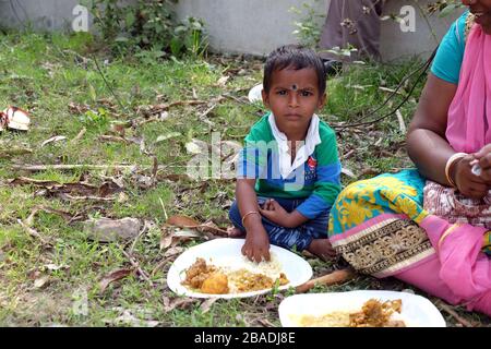 Ein kleiner Junge isst Mittagessen auf dem Boden im Dorf Kumrokhali, Westbengalen, Indien Stockfoto