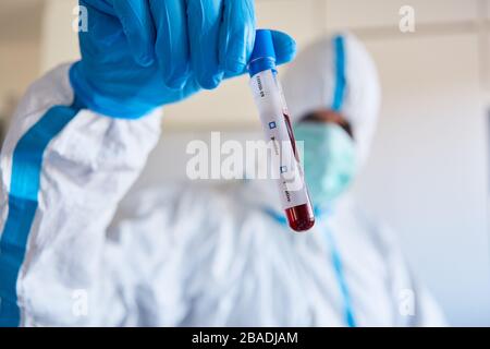 Forscher in Schutzkleidung mit Covid-19-Blutprobe für die Coronavirus-Forschung im Labor Stockfoto