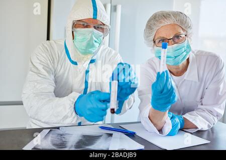 Radiologen in Schutzkleidung in der Klinik mit Blutproben von Covid-19-Patienten Stockfoto