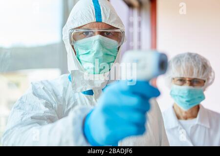 Medizinische Fachkräfte in Schutzkleidung, die kontaktloses Fieber im Covid-19-Testzentrum während der Epidemie des Coronavirus messen Stockfoto