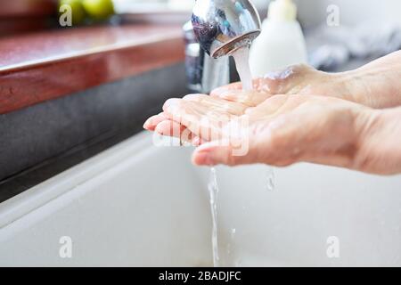 Ältere Frauen waschen die Hände mit Seife und Wasser im Badezimmer Stockfoto