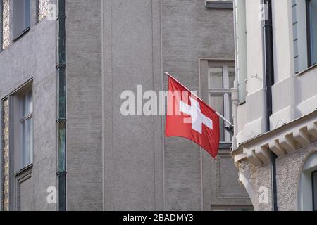Schweizerische Fahne hängt an der Gebäudefassade. Stockfoto