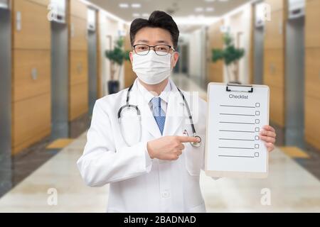 Asiatischer Mittelalter-Arzt mit einer Zwischenablage im Krankenhaus. Stockfoto