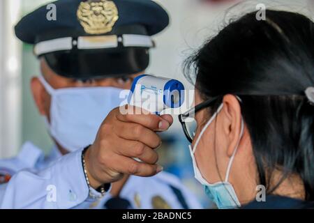 Pasay City. März 2020. Ein Passagier, der eine Gesichtsmaske trägt, hat ihre Temperatur überprüft, als sie für ihren Flug am Ninoy Aquino International Airport (NAIA) in Pasay City, den Philippinen am 27. März 2020 ankommt. Credit: Rouelle Umali/Xinhua/Alamy Live News Stockfoto