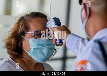 Pasay City. März 2020. Ein Passagier, der eine Gesichtsmaske trägt, hat ihre Temperatur überprüft, als sie für ihren Flug am Ninoy Aquino International Airport (NAIA) in Pasay City, den Philippinen am 27. März 2020 ankommt. Credit: Rouelle Umali/Xinhua/Alamy Live News Stockfoto