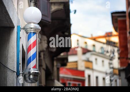 Frisierstange auf einer San José Straße. Schild mit internationalem Barbershop. Stockfoto