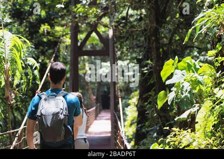 Touristen auf einer Hängebrücke, die einen üppigen tropischen Regenwald überquert. Monteverde foresta nebulosa, Santa Elena, Costa Rica. Ökotourismuskonzept. Stockfoto