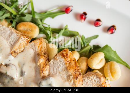 Huhn auf geriebenem Gnocchi in Sahnesauce aus Pilzen und Räucherkäse auf dem Tisch Stockfoto