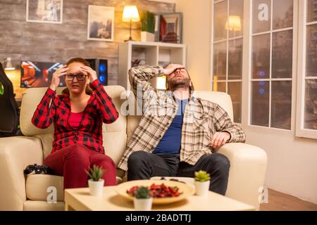 Verärgert und frustriert Spieler verlieren beim Spielen von Videospielen im Wohnzimmer am späten Abend Stockfoto