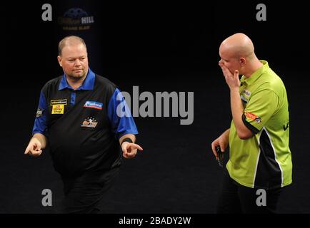 Raymond van Barneveld feiert das gewinnen eines Beins während des Finales, als Michael van Gerwen niedergeschlagen steht Stockfoto