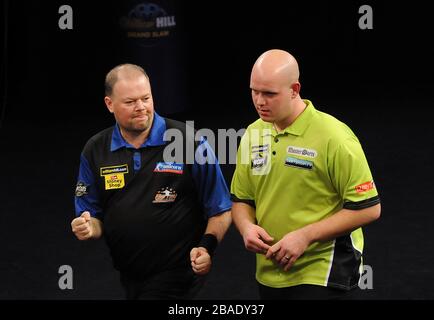 Raymond van Barneveld feiert das gewinnen eines Beins während des Finales, als Michael van Gerwen niedergeschlagen steht Stockfoto