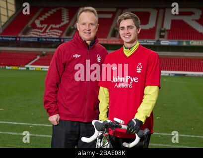 Nottingham Forest Manager Sean O'Driscoll mit dem Radfahrer Rowan Staszkiewicz Pitchside vor seiner 26 Meilen langen Radtour vom City Ground, Nottingham zum King Power Stadium, Leicester, um Geld für Prostate Cancer UK und die Alzheimer Society zu sammeln. Stockfoto