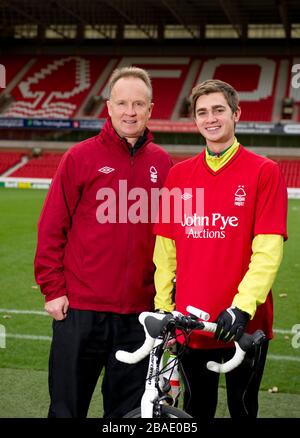 Nottingham Forest Manager Sean O'Driscoll mit dem Radfahrer Rowan Staszkiewicz Pitchside vor seiner 26 Meilen langen Radtour vom City Ground, Nottingham zum King Power Stadium, Leicester, um Geld für Prostate Cancer UK und die Alzheimer Society zu sammeln. Stockfoto