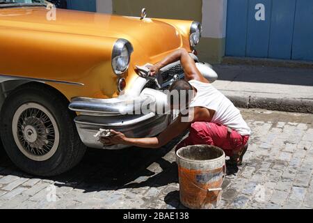 Straßenszene Alt-Havanna, Mann polieren ein 1950 Gold amerikanischen Auto Kuba Stockfoto