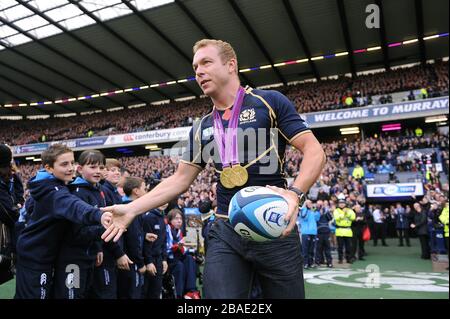 Großbritanniens Olympia-Goldmedaillengewinner Sir Chris Hoy trägt den Spielball auf das Spielfeld Stockfoto