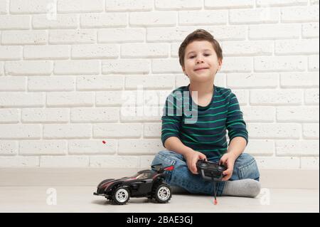 Junge mit Spielzeugauto gegen eine Ziegelwand Stockfoto