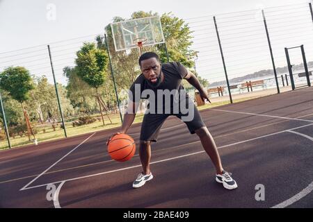 Aktivitäten Im Freien. Afrikanischer Mann spielt Basketball auf dem Platz Dribbling ernst Stockfoto