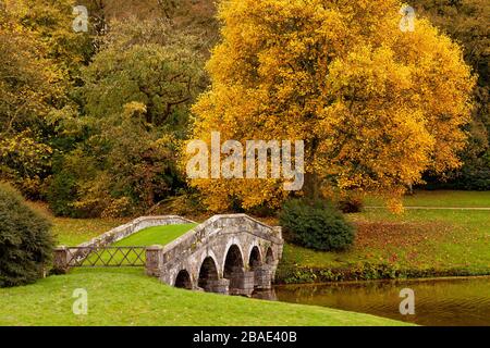 Herbstfarbe rund um die Palladian-Brücke in Stourhead Gardens, Wiltshire, England, Großbritannien Stockfoto