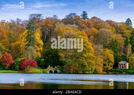 Die leuchtende Herbstfarbe umgibt den See in Stourhead Gardens, Wiltshire, England, Großbritannien Stockfoto