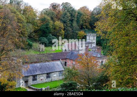 Die Pfarrkirche St Peter's at Stourhead ist von Wald umgeben, das Herbstfarbe zeigt, Wiltshire, England, Großbritannien Stockfoto