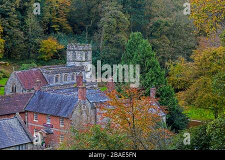 Die Pfarrkirche St Peter's at Stourhead ist von Wald umgeben, das Herbstfarbe zeigt, Wiltshire, England, Großbritannien Stockfoto