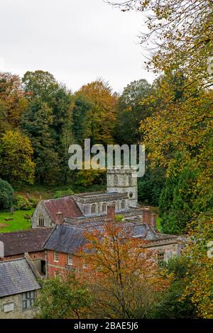 Die Pfarrkirche St Peter's at Stourhead ist von Wald umgeben, das Herbstfarbe zeigt, Wiltshire, England, Großbritannien Stockfoto