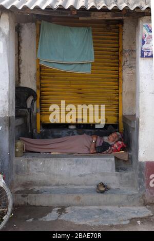 Ein Mann schläft vor seinem Laden in Chunakhali Dorf, Westbengalen, Indien Stockfoto