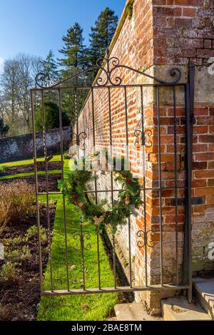 Dekorative Weihnachtskränze an einem Tor im ummauerten Garten im Stourhead House, Wiltshire, England, Großbritannien Stockfoto