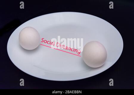 Soziale Distanziertheit der Stunde. Eier auf weißem Teller, die soziale Distanzierung darstellen, getrennt Stockfoto